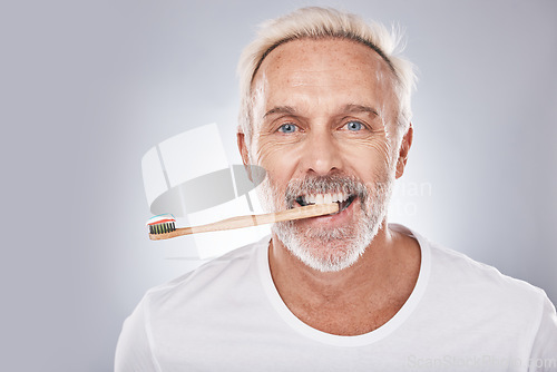 Image of Grooming, dental hygiene and man brushing teeth for mouth health, happy smile and clean teeth on a studio background. Healthcare, oral care and face portrait of a senior model with a toothbrush