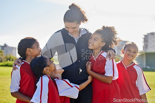 Image of Girl football team, coach celebration and hug for success, teamwork and group diversity on grass pitch. Young female kids, soccer coaching and love for mentor woman on field for happiness in sunshine