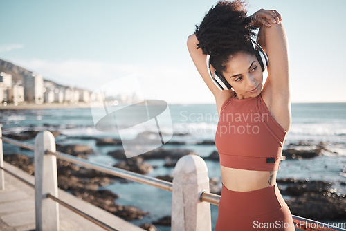 Image of Beach, fitness and woman doing a stretching exercise before running or training for a race or marathon. Health, sports and female athlete doing an arm warm up before a cardio workout by the ocean.