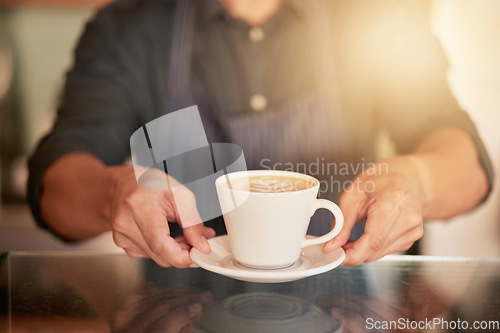 Image of Coffee, cafe and hands of waiter with cup on table in restaurant. Small business, cappuccino art or barista, man or server holding fresh, delicious or hot mug of caffeine or espresso in shop or store