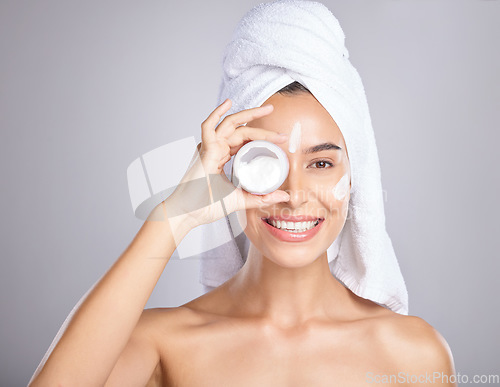 Image of Woman, face and smile for skincare cream, moisturizer or lotion isolated on a grey studio background. Portrait of happy female holding cosmetic creme for beauty, soft or smooth skin in dermatology