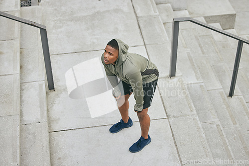 Image of Breathe, tired and sweating black man, athlete and fitness break on stairs of city workout. Top view of runner, breathing and sports fatigue on steps of training challenge, exercise or cardio running