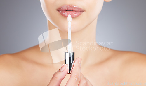 Image of Woman, lips and lip gloss application for beauty, makeup shine and skincare wellness in grey background studio. Model, lipstick tool or brush for cosmetics dermatology glow or luxury salon product