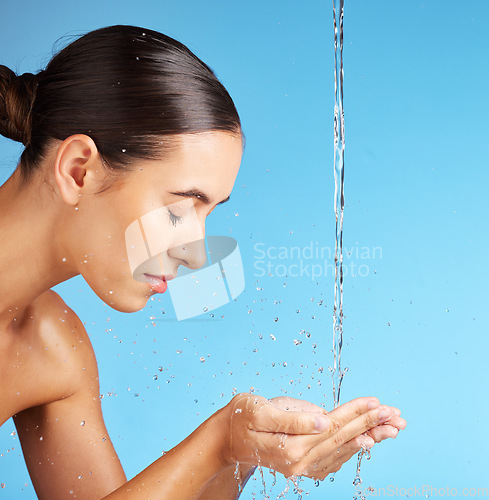 Image of Woman, hands and water for face wash, skincare hydration or hygiene against a blue background. Beautiful female model in facial cleaning, washing or cleansing for skin rehydration or dermatology