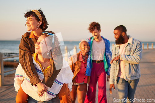 Image of Summer, diversity and piggyback with friends on the promenade by the sea or ocean during vacation. Water, holiday and friendship with a man and woman friend group walking while bonding together