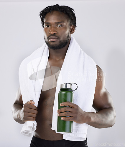 Image of Exercise, fitness and black man with a towel and water for sports training in studio. Health and wellness of a sexy male bodybuilder model thinking about workout, goal and body progress with a bottle