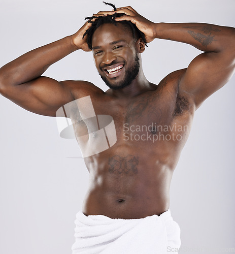 Image of Black man in towel and skin in portrait, shower and hygiene, grooming and beauty isolated on studio background. Smile, muscle and abs, strong and skincare glow, body care with natural cosmetics