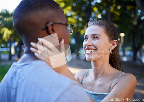 Image of Love, interracial or couple of friends in a park bonding on a romantic date in nature in a marriage commitment. Embrace, relaxed black man and happy woman enjoying quality time on a holiday vacation
