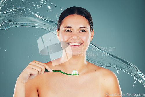 Image of Happy, grooming and portrait of a woman brushing teeth isolated on a blue background. Water splash, health and face of a clean, smiling and young model taking care of dental hygiene with toothpaste