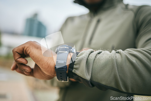 Image of Fitness, training and hand of a man with a watch for progress, exercise monitor and tracking health in Germany. Goal, performance and runner reading the time after running for cardio in the city