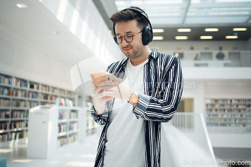 Image of Phone music, headphones and student in library, university, or college research on mental health, wellness and education. Bookshelf, knowledge and creative, geek man listening to audio on mobile app