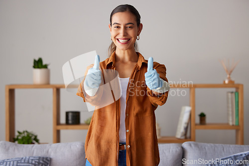 Image of Happy woman, thumbs up and cleaning service with a smile in a house or apartment living room for safety with gloves. Female cleaner showing hand sign to clean dirt, dust and bacteria at home