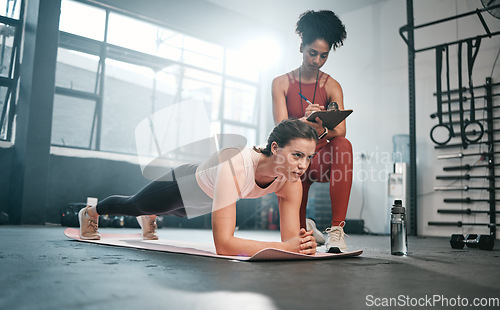 Image of Personal trainer, fitness and clipboard with a black woman coaching a client in a gym during her workout. Health, exercise or training and a female athlete doing a plank with her coach writing notes