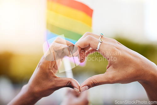 Image of LGBTQ, pride flag and hands with a heart sign for love, equality and solidarity of a gay couple. Rainbow, freedom and closeup of lesbian women with a hand symbol at a gay pride celebration festival.