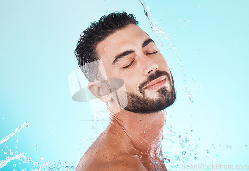 Image of Water, splash and skincare with face of man for shower, self care and natural cosmetics. Luxury, hydration and refreshing with model for dermatology, wellness and cleaning on blue background studio