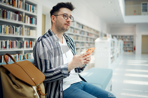 Image of Smartphone, library and student with university idea, knowledge or mindset for education, college or research with wifi services. Campus, bookshelf and man relax, thinking with cellphone and backpack