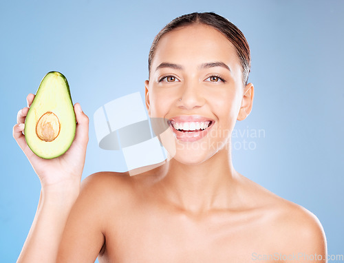 Image of Woman, studio portrait and avocado skincare with smile, health or wellness by blue background. Model, fruit and face with natural cosmetic beauty, glow or healthy aesthetic with self care by backdrop