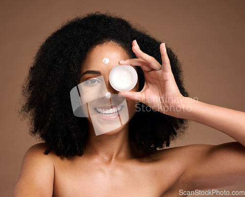 Image of Portrait, container and beauty with a model black woman in studio on a brown background for skin treatment. Face, product and skincare with an attractive young female posing to promote antiaging care