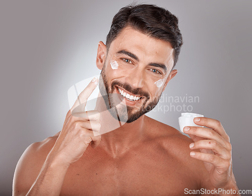 Image of Man, skincare and cream in studio portrait with smile, happiness or self care by grey gradient backdrop. Cosmetic model, skin glow or luxury dermatology product in hand for wellness, facial or health