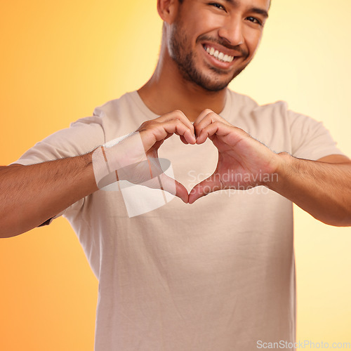 Image of Portrait, heart and hands of man in studio isolated on a yellow background. Love, romance and happy male model with hand gesture for romantic emoji, care symbol or kindness, support or thank you.