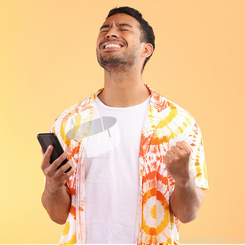 Image of Winner, celebration and man with phone in studio isolated on yellow background. Winning, cellphone or happy male model holding mobile smartphone while celebrating goals achievement, target or success