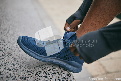 Image of Hands, city and black man tie shoes and getting ready for running, workout or exercise. Sports fitness, wellness and male runner tying sneaker lace and preparing for training jog on street outdoors.