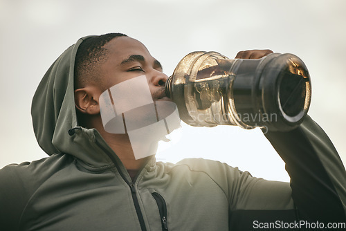 Image of Fitness, health or black man drinking water after training, exercise or workout for body hydration. Thirsty runner, bottle or tired sports athlete relaxing with goals or motivation resting in Chicago