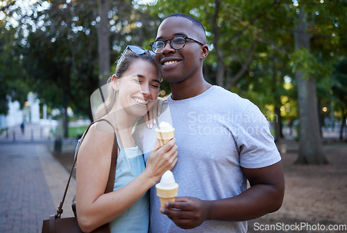 Image of Happy, interracial and couple eating ice cream in a park on a date, anniversary or walk together. Love, smile and man and woman with a sweet dessert while walking in nature with romantic affection