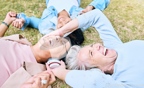 Image of Seniors, laughing or people and music headphones in silent disco, retirement friends fun or bonding community wellness. Smile, happy or elderly women lying on nature park grass and listening to radio