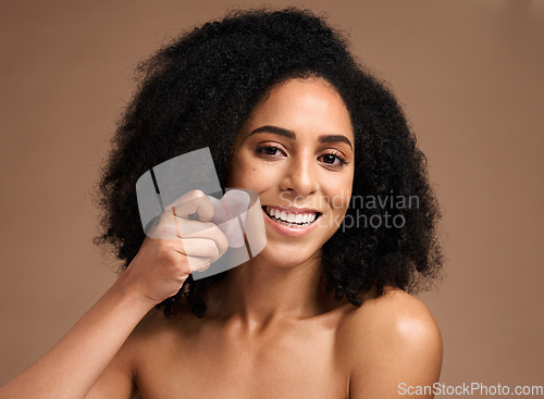 Image of Woman, studio portrait and crystal guasha for skincare, smile or cosmetic facial massage by backdrop. Black woman, model and self care with rose quartz stone for face glow, skin wellness or aesthetic