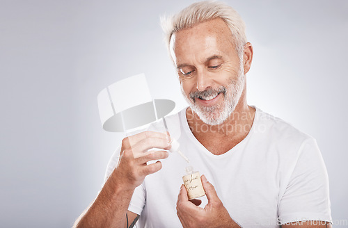 Image of Man, skincare or face oil on studio background in mature self care, product healthcare or aging wellness. Smile, happy model or facial serum for beard growth, beauty collagen or senior dermatology