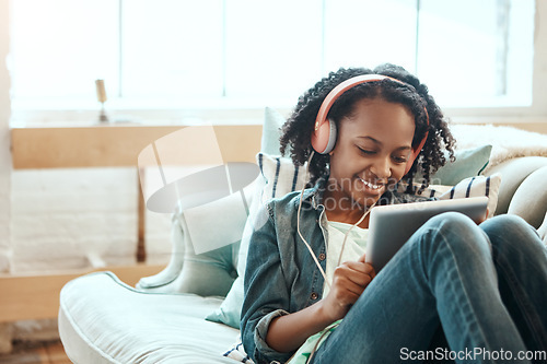 Image of Tablet, headphones and black girl on the sofa to relax while listening to music, radio or podcast. Rest, technology and African child watching a video on mobile device in her living room at home.