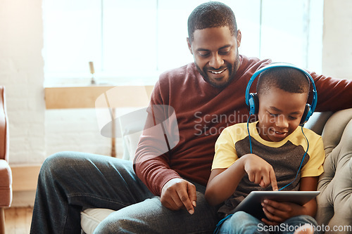 Image of Tablet, happy and dad with his son on a sofa watching a funny, comic or meme video on social media. Relax, smile and African man streaming a movie with child on mobile device while relaxing together.