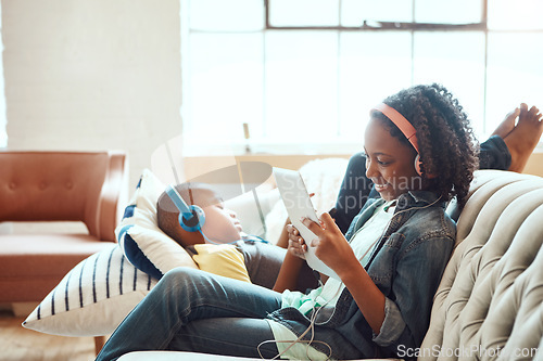 Image of Siblings, tablet and headphones for relax on sofa in the living room enjoying entertainment or wifi at home. Happy sister and brother relaxing on couch listening to music or online streaming indoors