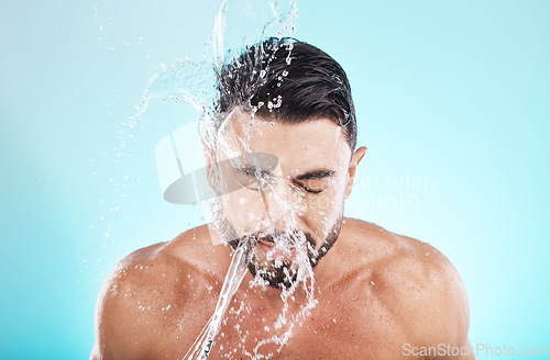 Image of Man, water splash and face cleaning in blue background studio for grooming hygiene, skincare wellness and cosmetics dermatology care. Model, facial spa and body washing or morning beauty routine