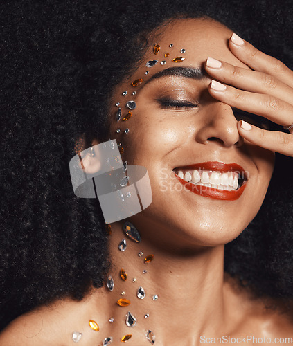 Image of Woman, face or fashion body rhinestones on black background studio in jewels sparkle, festival diamonds or creative party crystal. Zoom, hand or happy afro beauty model, skin gem or makeup cosmetics