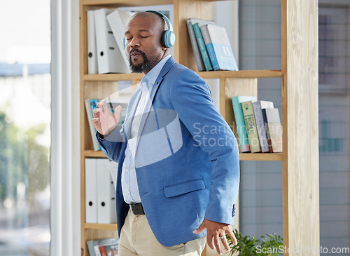 Image of Music, dance and headphones with a business black man manager dancing in his office at work. Wellness, radio and freedom with a senior male worker listening or streaming audio while working