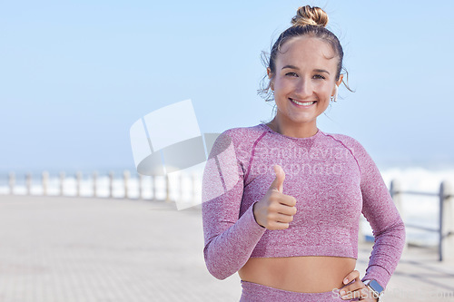 Image of Thumbs up, running and like with a sports woman or runner by the beach for cardio or endurance. Winner, motivation and fitness with a female athlete saying yes with a hand gesture outdoor