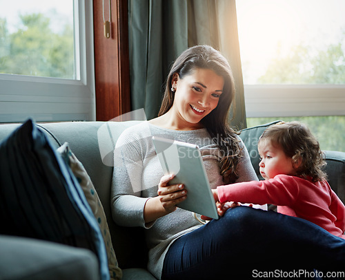 Image of Mother, tablet and baby playing on sofa in living room for entertainment, bonding or time together at home. Happy mom with cute little daughter, child or kid relaxing on the couch with touchscreen