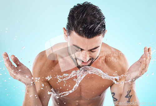 Image of Skincare, water splash and man in a studio for a wellness, health and self care body routine. Cosmetics, hydration and male model with natural dermatology facial treatment isolated by blue background