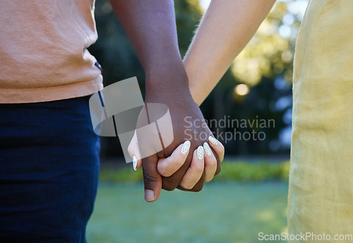 Image of Interracial, couple holding hands and trust, love outdoor in nature and commitment, support in relationship. Together in park, black man with woman, hand zoom and care, romantic date with partnership