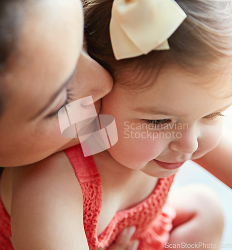 Image of Mother kissing her girl baby on her cheek while playing, bonding and spending time together. Happy, smile and girl infant child sitting with her mom in their modern family home with love with care.