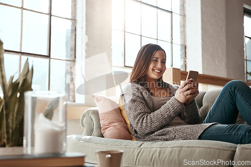 Image of Happy, woman and phone for social media on a sofa, texting and chatting on dating app in her home. Girl, smartphone and text conversation in a living room, smile and relax while streaming and resting