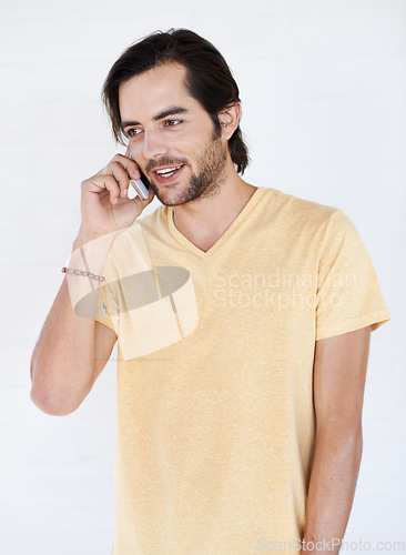 Image of Phone call, talking and man in studio, happy and relax while standing on white background space. Young, phone and hand guy enjoying casual call, conversation and speaking while chilling and isolated