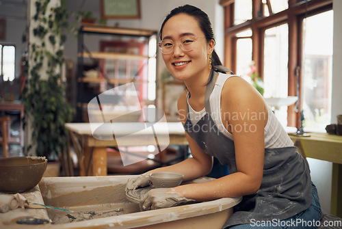 Image of Pottery, startup business and creative woman portrait in her workshop for art with hands in mud. Asian artist with potter wheel for clay or ceramic retail industry, trade or production with pride