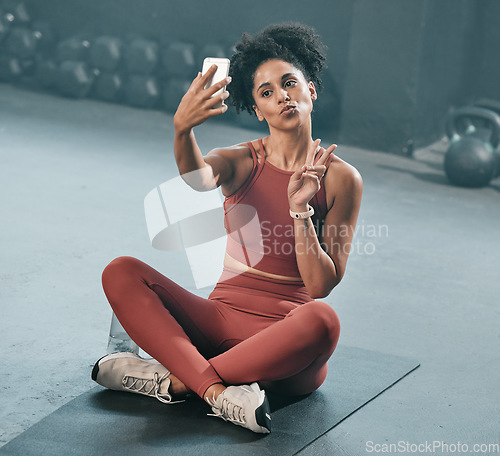 Image of Fitness, selfie and woman on a gym floor with phone, peace and hand sign before exercise routine. Workout, picture and peace gesture by black woman posing for photo after training, emoji and relax