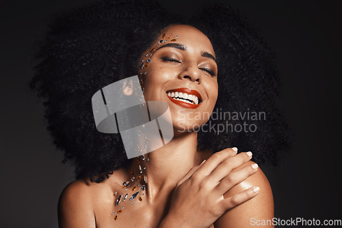 Image of Woman rhinestones, face or body art jewels on black background studio in fashion sparkle, festival accessory or creative party crystals. Happy smile, afro or beauty model skin or makeup cosmetic gems