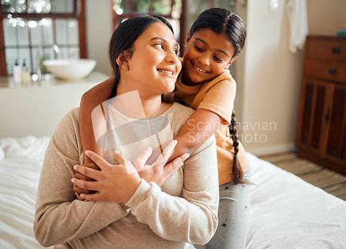 Image of Love, hug and mother and daughter on a bed, bonding and sharing a sweet moment in their home together. Family, happy and girl embrace woman, smile and relax in a bedroom, content and cheerful