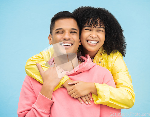 Image of Couple, smile and hug in portrait with happiness, love and commitment with fashion isolated on blue background. Interracial relationship, commitment and together in studio with happy people and trust