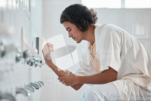 Image of Islam, ablution and man washing before prayer in bathroom at mosque in Iran, spiritual cleaning ritual. Islamic culture, water and worship, muslim guy in cleansing care routine to prepare for praying